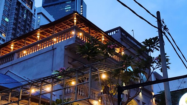 Ein modernes Gebäude mit Balkon und Lichterkette, umgeben von anderen Hochhäusern.
