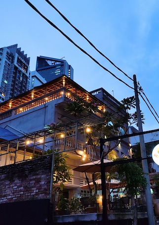 A modern building with a balcony and string lights, surrounded by other high-rise buildings.