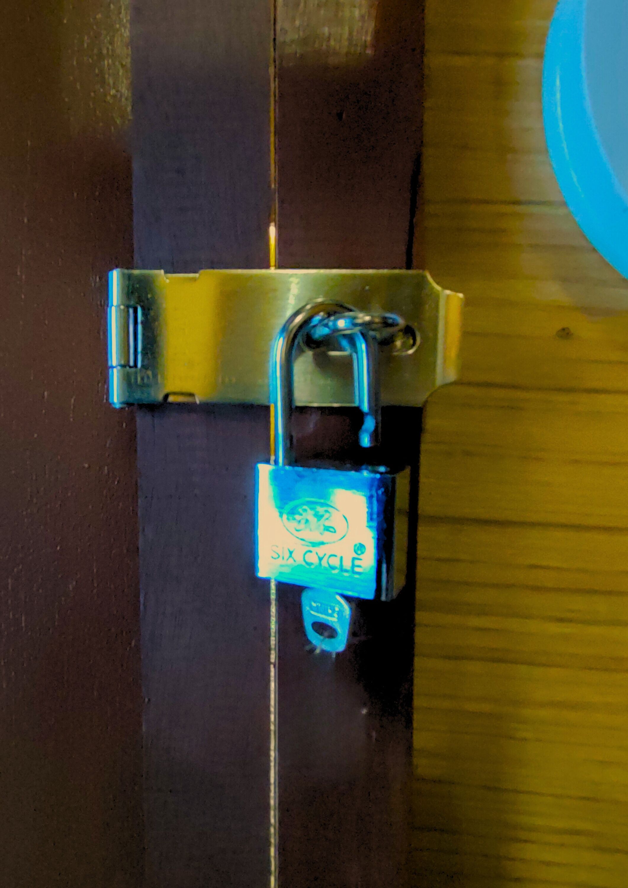 Un cadenas sur une porte dotée d’un loquet métallique.
