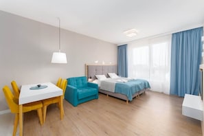 A modern hotel room with a bed, a desk, and a chair.