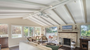 A spacious living room with a fireplace, a sofa, and a dining area with outdoor seating.