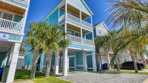 Un immeuble de deux étages situé en bord de mer, doté de balcons, d’une piscine privée et de palmiers.