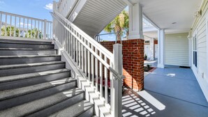 A covered outdoor area with a staircase leading to a brick wall, a garage door, and a clear sky. - Tupelo Bay Villas 314 - Three Bedroom, Two Bath Condo in Golf Community (Garden City Beach)