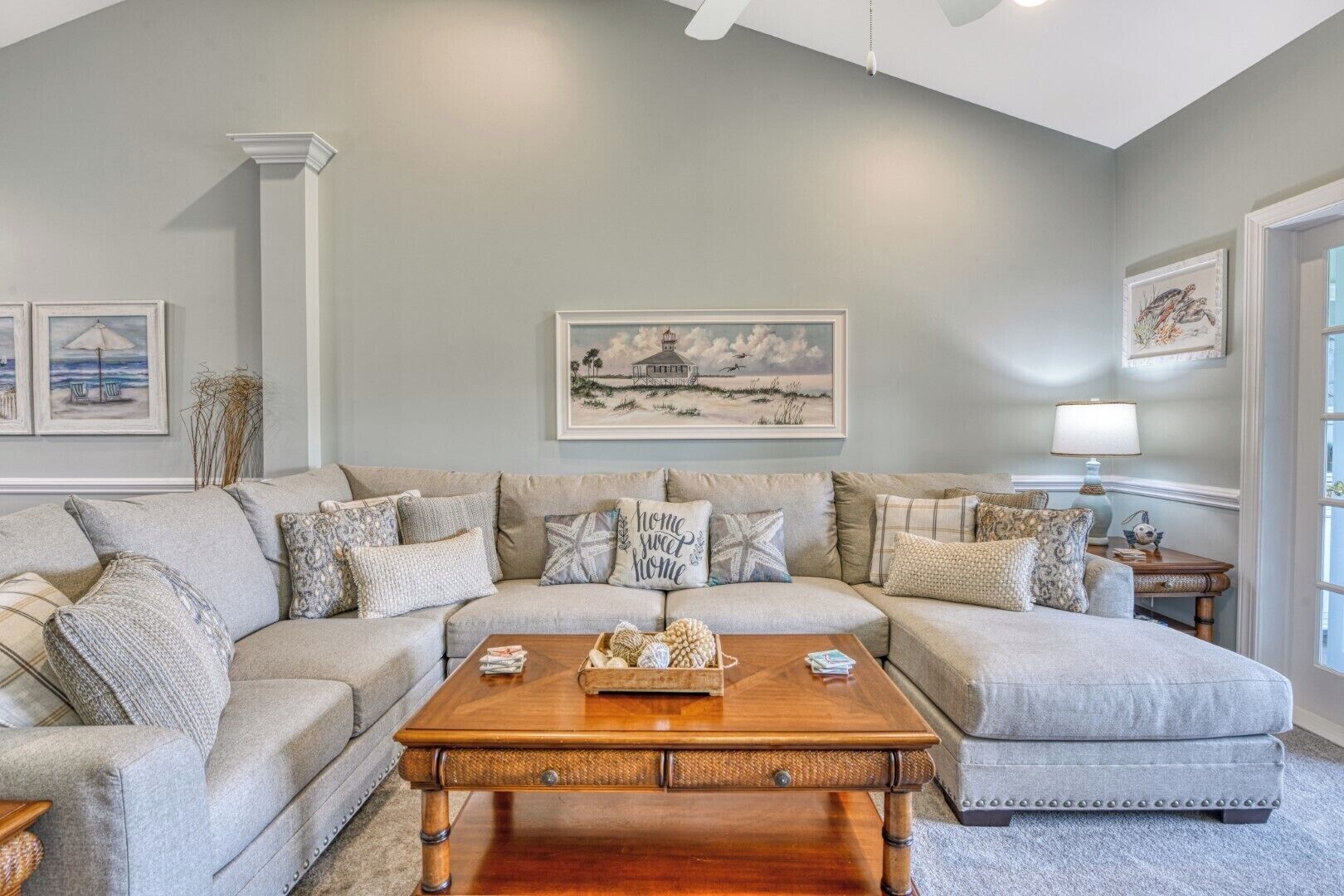 A living room with a sectional sofa, a wooden coffee table, and framed artwork on the walls.