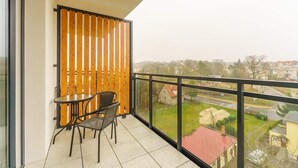 A balcony with a table and chairs, a wooden slat partition, and a view of a residential area. - Stylish Studio with Balcony | Parking | 750 m to the Beach (Miedzyzdroje)