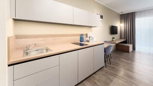 A modern kitchen with a built-in sink, a coffee maker, and a flat-screen TV mounted on the wall. - Stylish Studio with Balcony | Parking | 750 m to the Beach (Miedzyzdroje)