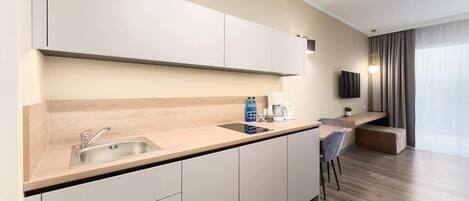 Una cocina moderna con un lavamanos integrado, una cafetera y un televisor de pantalla plana montado en la pared.