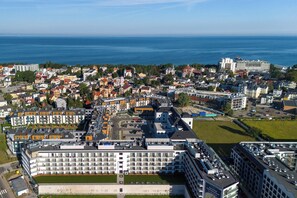 A coastal cityscape with a prominent hotel featuring multiple floors and balconies.