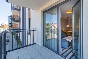 A modern apartment with a balcony, a sliding glass door leading to a living area, and a staircase to an upper floor.