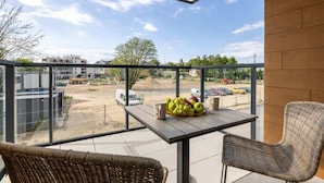 A balcony with wicker chairs, a table with fruit, and a view of a construction site.