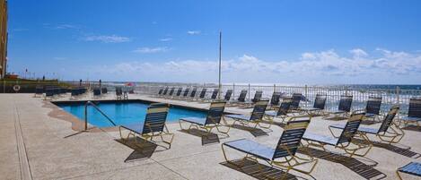 A poolside area with sun loungers and a view of the ocean.