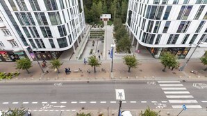 A modern urban intersection with pedestrian pathways, a bicycle lane, and a central plaza with trees and seating areas.