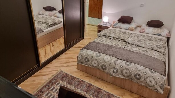 A bedroom with a bed, a nightstand, a mirror, and a wardrobe. - Big Downtown 2 Bedroom Apartment across National Theater  (Beograd)