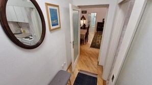 A narrow hallway with a bench, a mirror, and a rug leading to a dining area. - Big Downtown 2 Bedroom Apartment across National Theater  (Beograd)