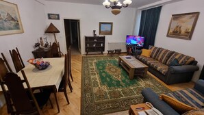 A living room with a dining table, sofa, and TV. - Big Downtown 2 Bedroom Apartment across National Theater  (Beograd)