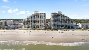 A beachfront hotel with multiple high-rise buildings, a sandy beach, and ocean waves. - Condo with Private Balcony & Beach Views Near Pier (Garden City Beach)