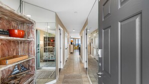 A hallway with a wooden shelf, a red bowl, and a patterned rug. - Condo with Private Balcony & Beach Views Near Pier (Garden City Beach)