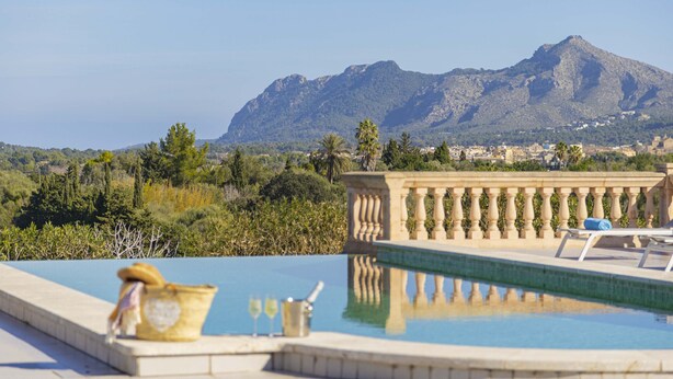 Ein Pool mit Blick auf Berge, einer Brüstung und einer Steinmauer.