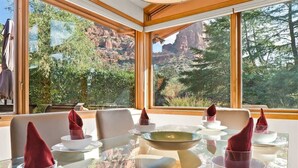 A dining area with a glass table, chairs, and a view of red rock formations.