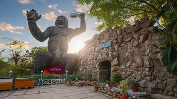 A large gorilla statue holding a plate, a stone wall, and a sign that reads "Khao Long".