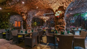 Ristorante interno con pareti in pietra e tavoli apparecchiati per consumare un pasto.