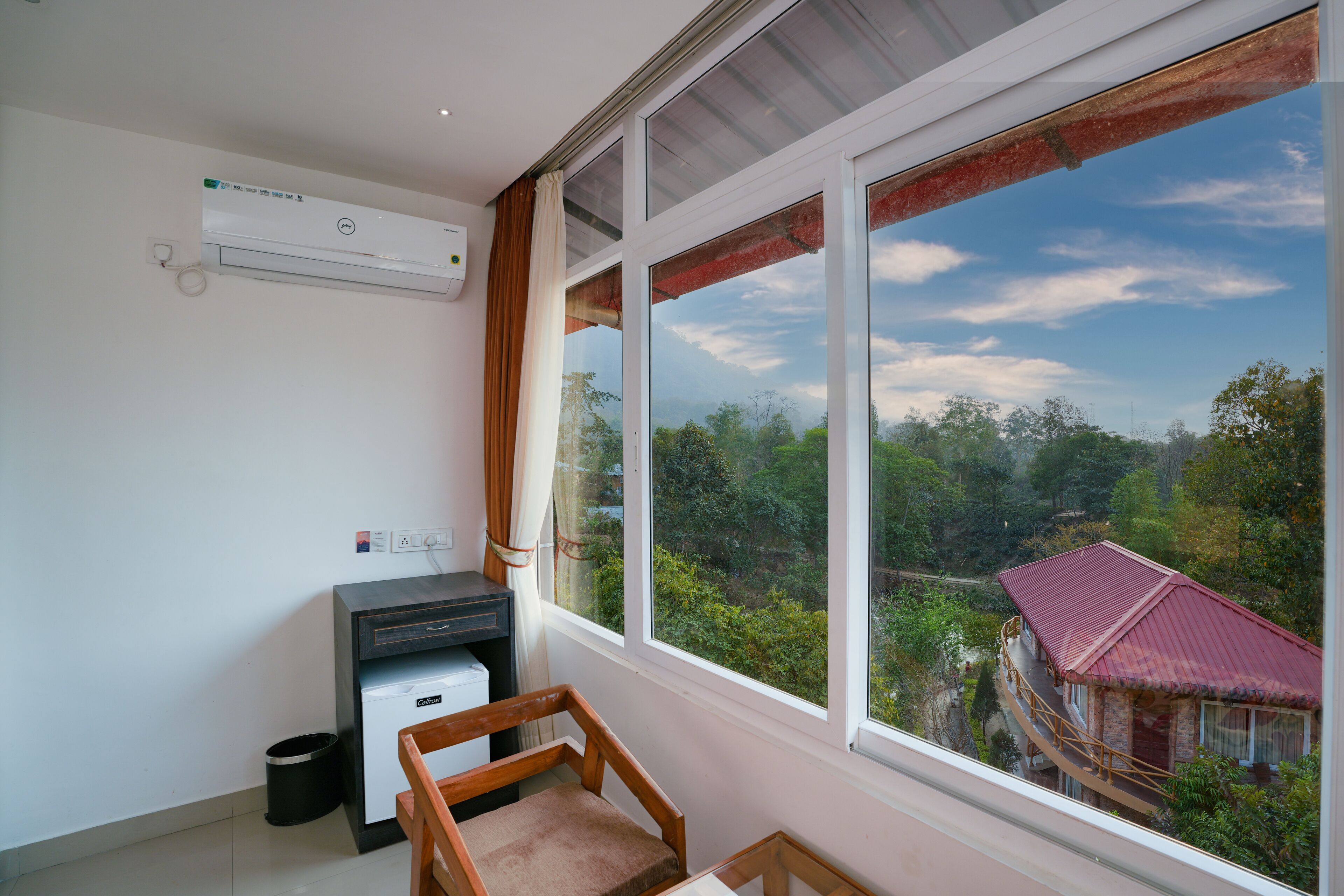 A room with a large window, a desk, a chair, and an air conditioning unit.
