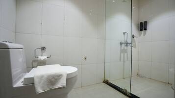 A bathroom with a toilet, a glass-enclosed shower, and white tiled walls.