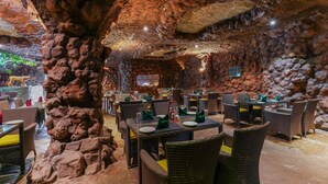Un ristorante con interni simili a una grotta, caratterizzato da pareti in pietra e tavoli apparecchiati per la cena.