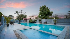 Una piscina rettangolare con bordi piastrellati, circondata da un muretto basso e piante in vaso.