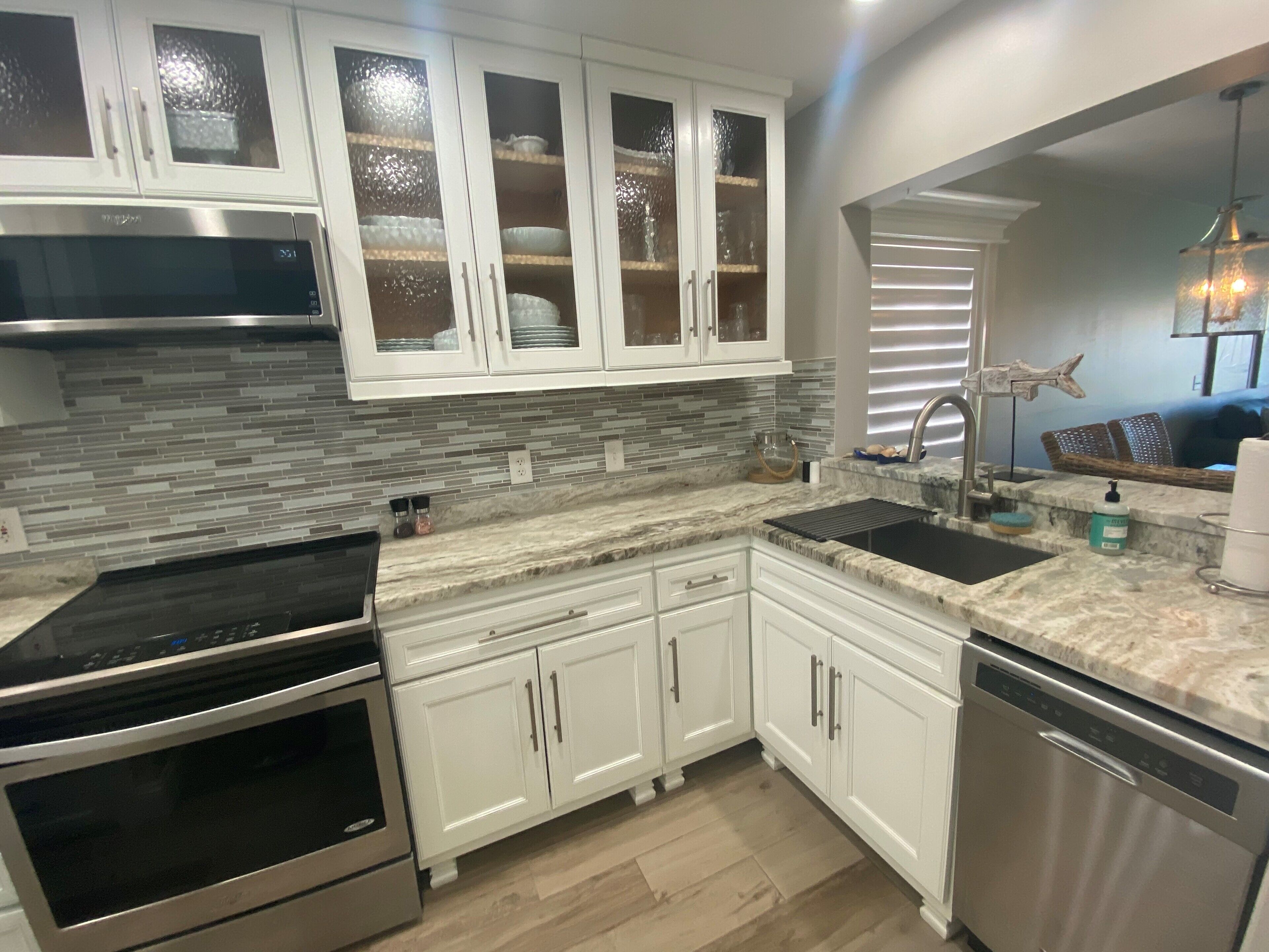 A modern kitchen with white cabinets, a stainless steel range, and a dishwasher.