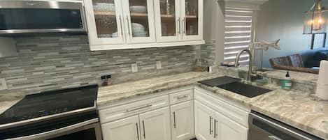 A modern kitchen with white cabinets, a stainless steel range, and a dishwasher.