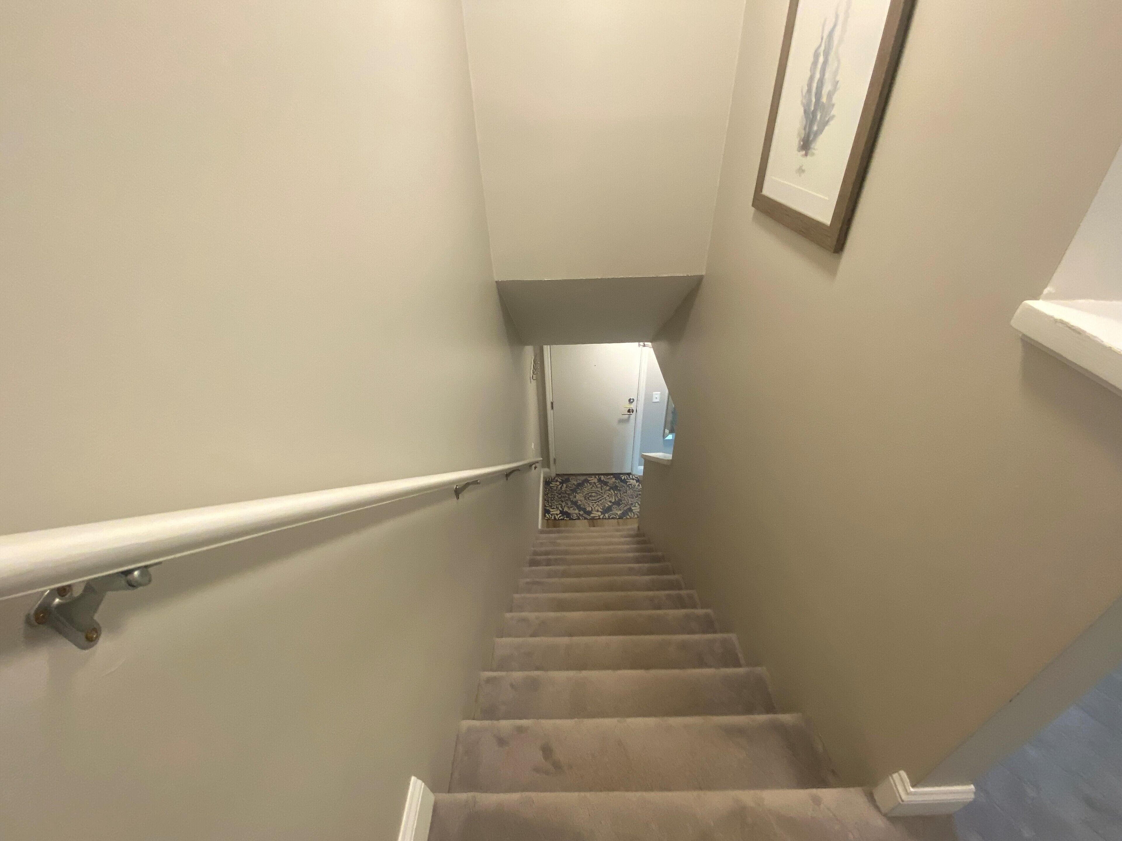 A carpeted staircase with a handrail, leading to a room with a patterned floor.