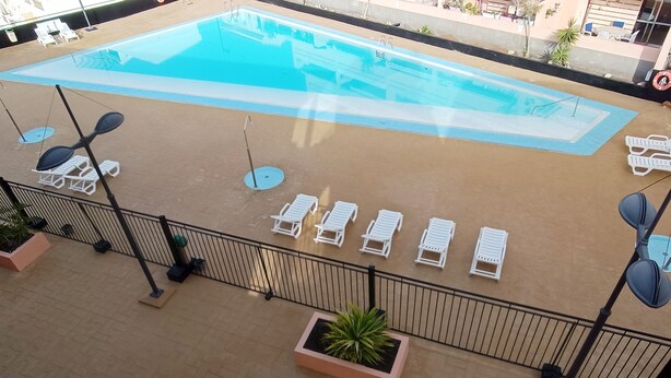 A rooftop pool area with white lounge chairs and a clear blue pool. - Apartamento Idaira Sun (Los Cristianos)