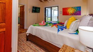 Een slaapkamer met een bed, een televisie, een schilderij en uitzicht op de omgeving.