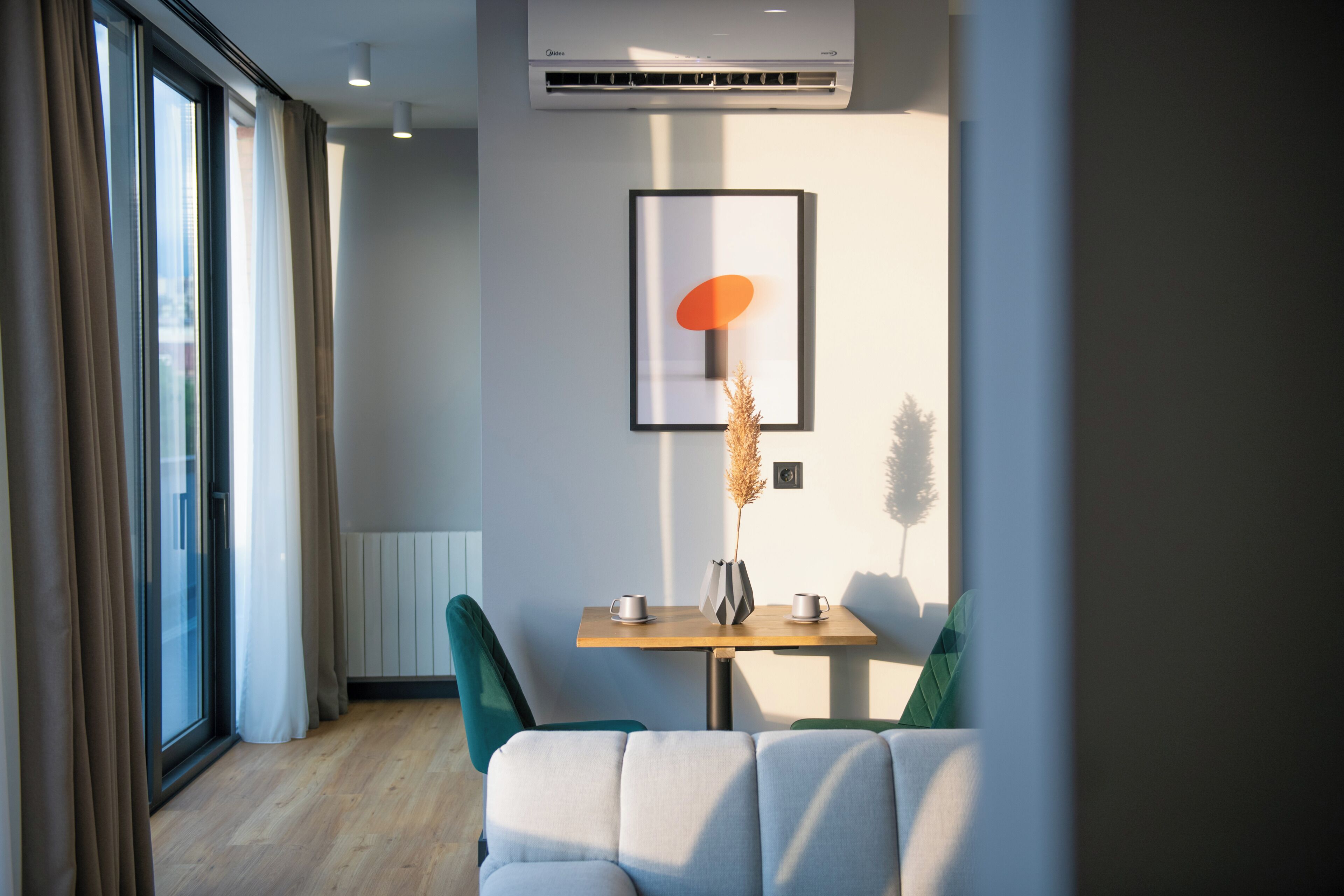 Una habitación moderna con una mesa de madera, dos sillas, un sofá y un cuadro en la pared.