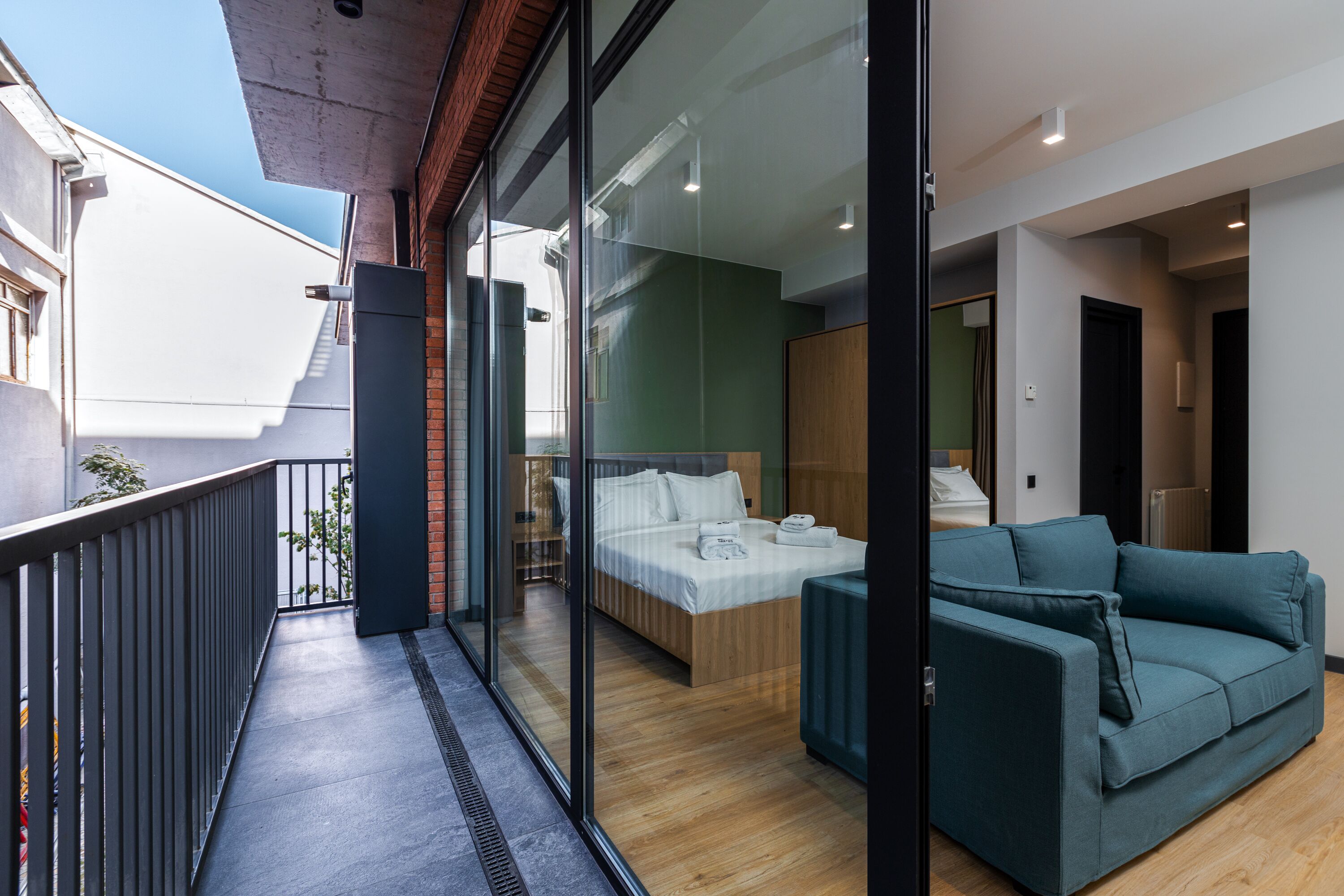 Une chambre d’hôtel moderne avec balcon, un lit, un canapé et une vue sur la ville.