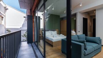 Une chambre d’hôtel moderne avec balcon, un lit, un canapé et une vue sur la ville.