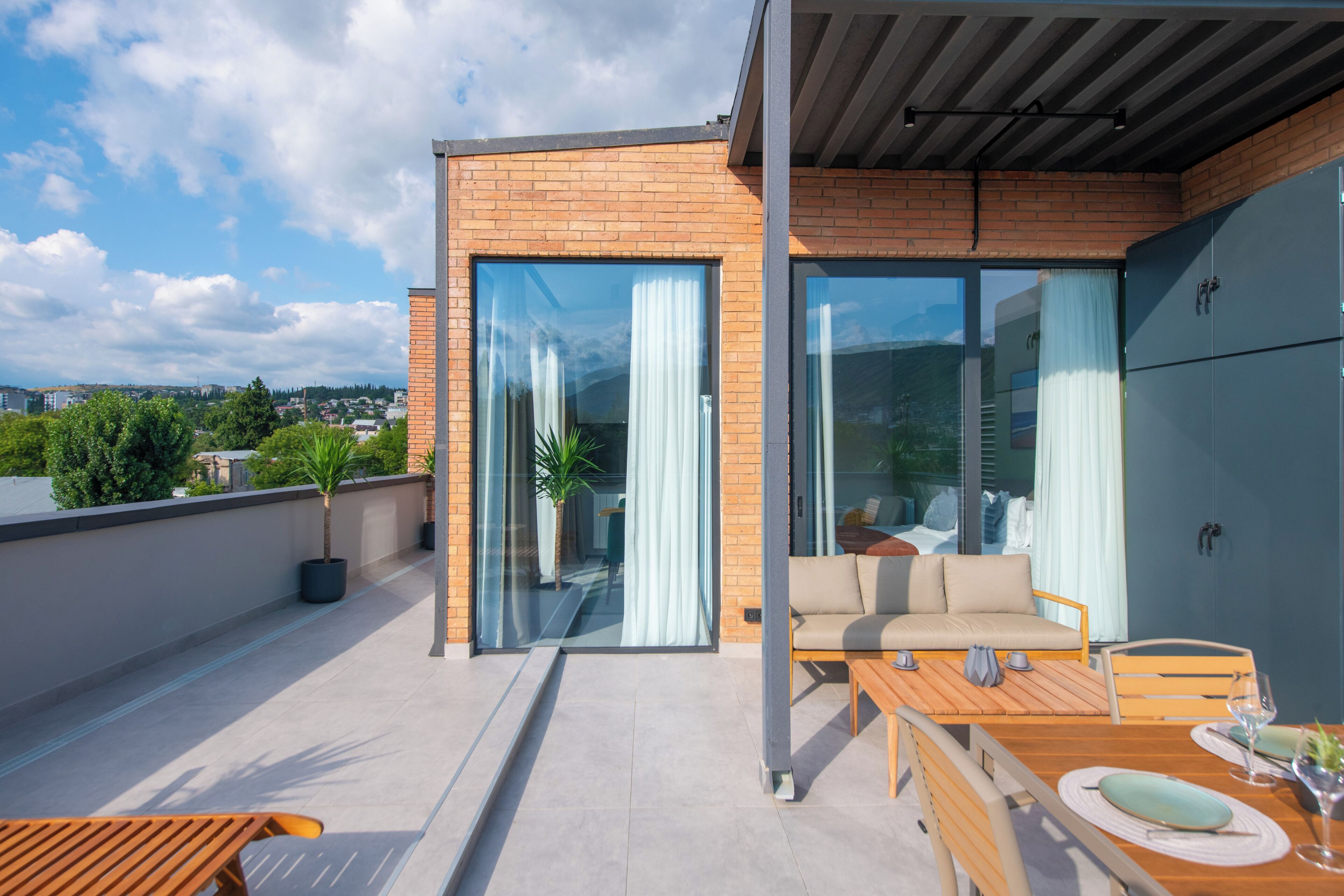 Una terraza moderna al aire libre con zona de comedor, un sofá y una planta en maceta.