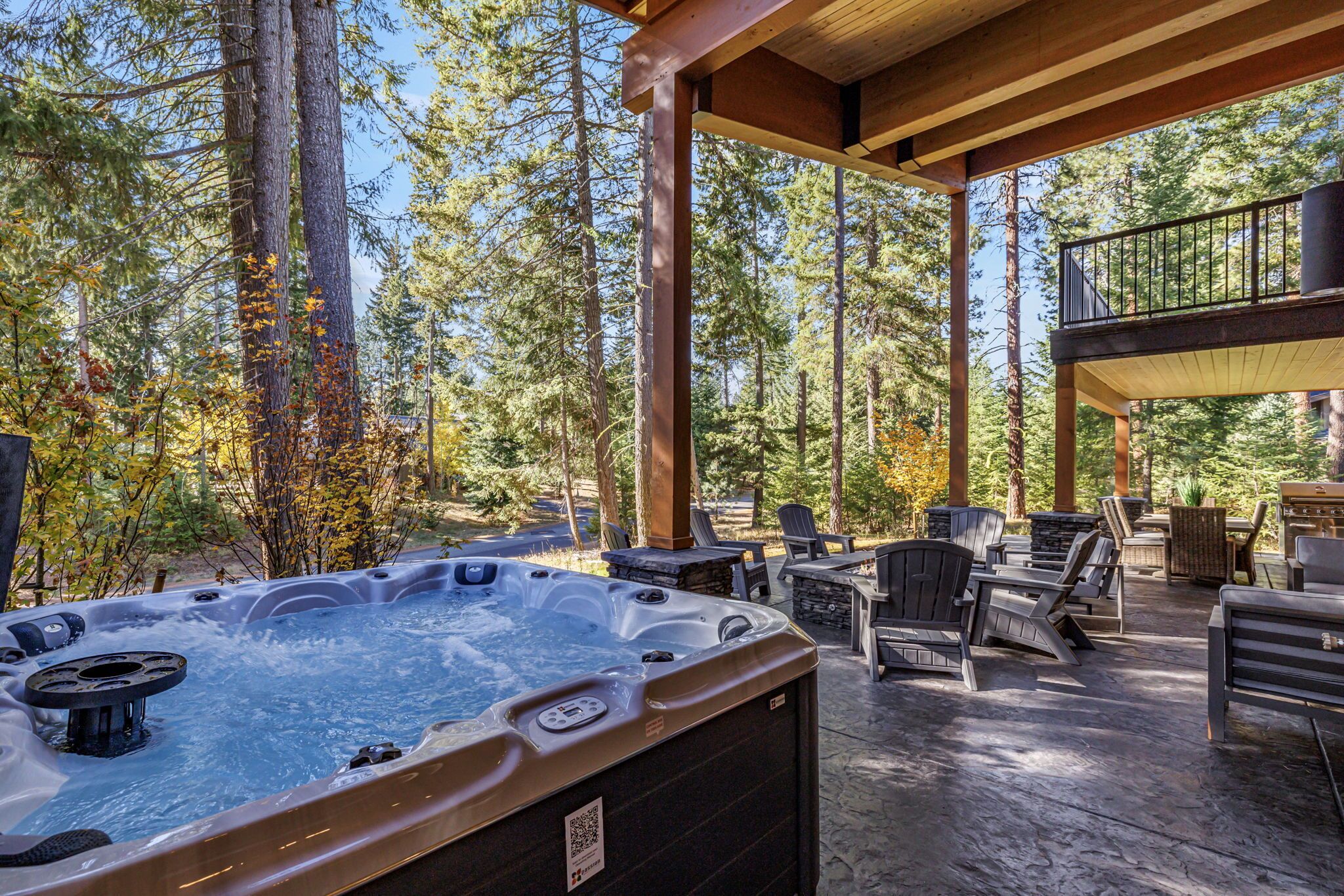A hot tub area with seating and a view of a forest.