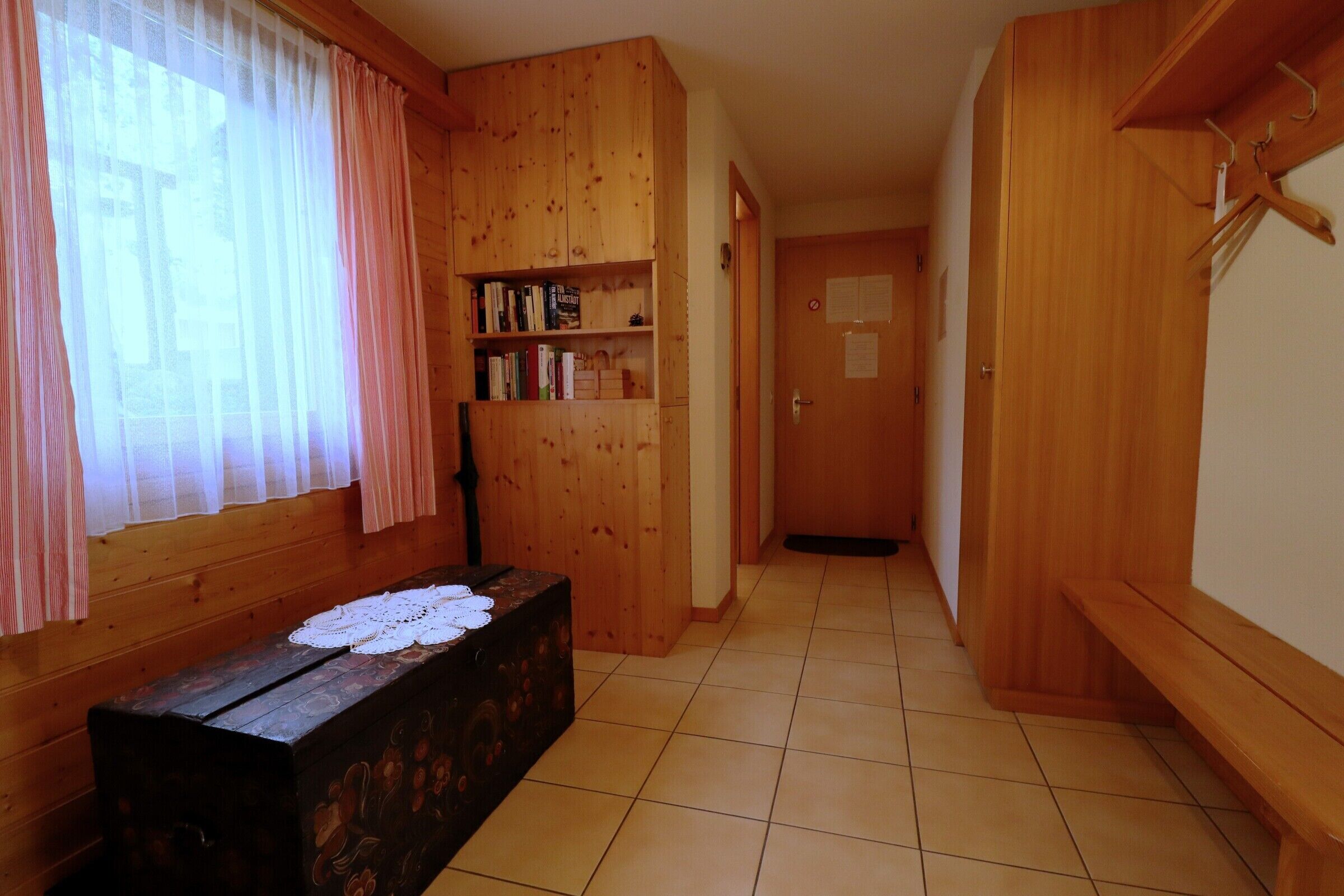 Un couloir aux murs en bois, avec un banc et une bibliothèque.