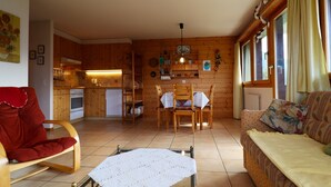 A cozy cabin interior with a dining area, wooden walls, and a sofa. - Exterior : Apartment on the lower ground floor of a building, for 4 people close to the hotel/restau (St-Luc)