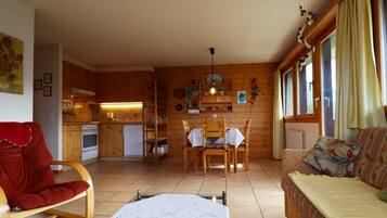 L’intérieur d’un chalet chaleureux, avec un coin repas, des murs en bois et un canapé.