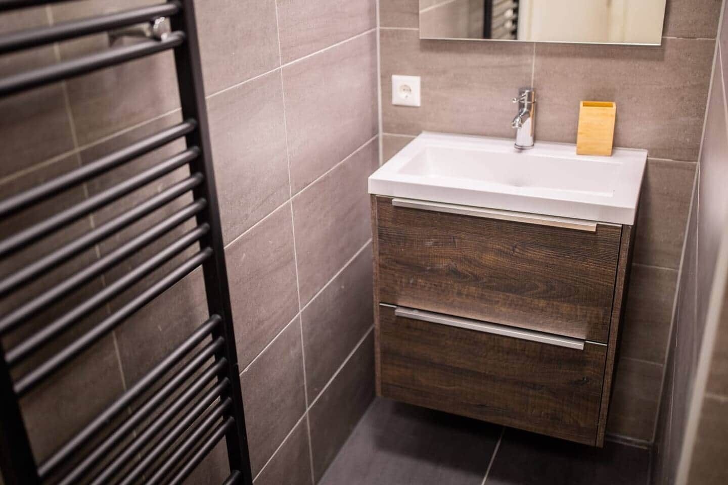 A bathroom with a white sink, dark wooden cabinet, and a towel rack.