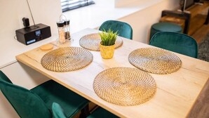 Une table à manger avec des sets de table en fibres tressées, une petite plante en pot et un appareil électronique noir placé à gauche.