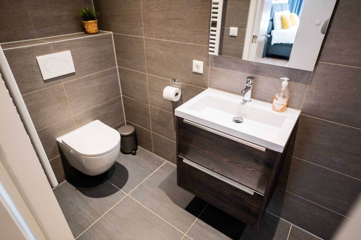 A modern bathroom with a toilet, sink, and mirror.
