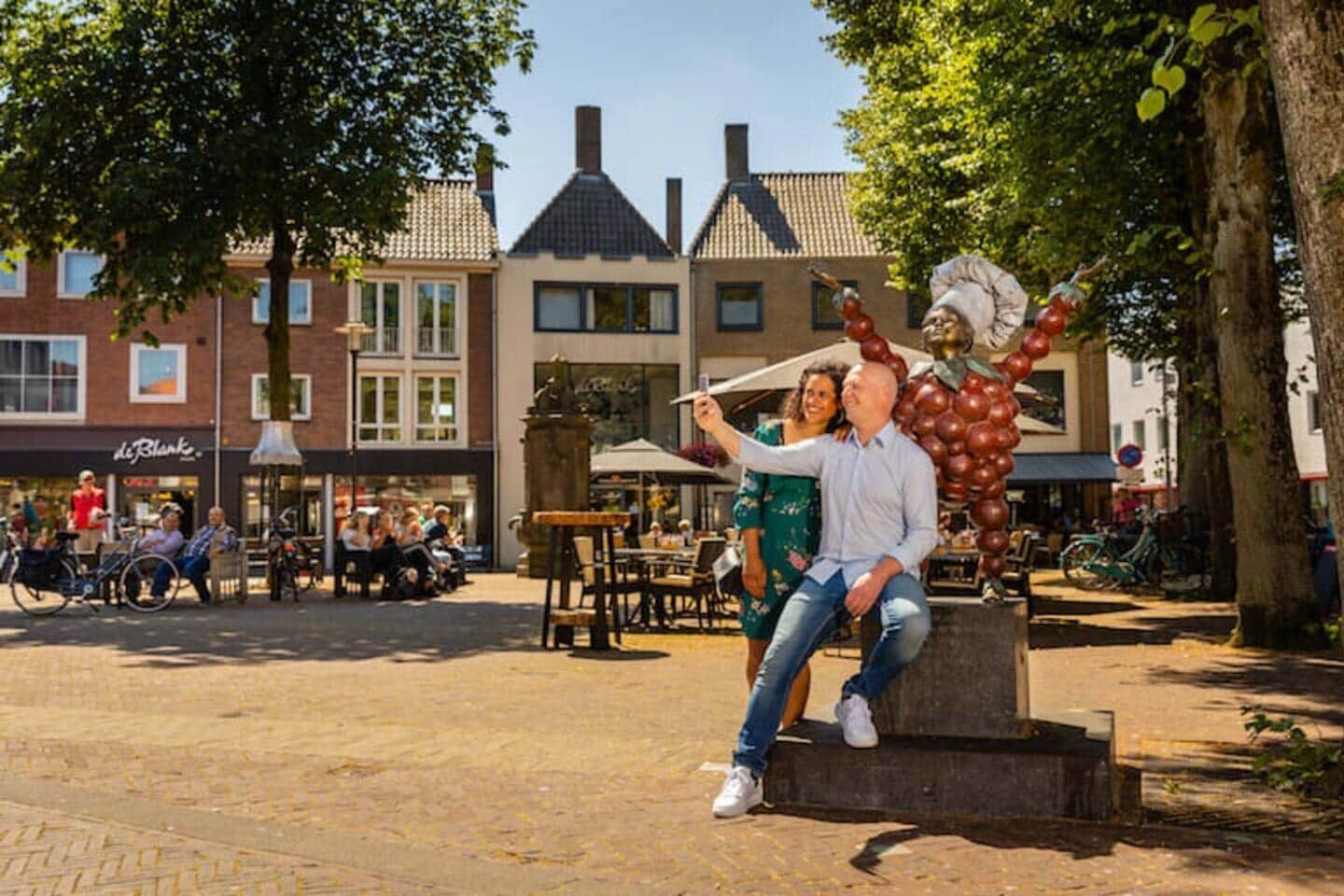 A couple taking a selfie in a public square with buildings in the background.
