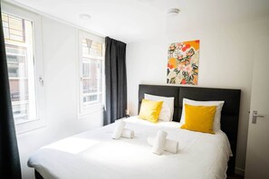 A hotel room with a bed, a window, a painting, and a door. - Happy 50m² Apartment (WE-39-C) (Tiel)