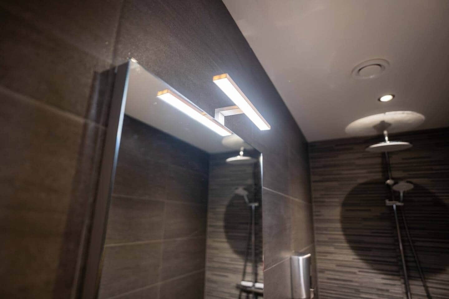 Ein modernes Badezimmer mit Duschkabine aus Glas, einem Wandhandtuchhalter und einer Deckenleuchte.