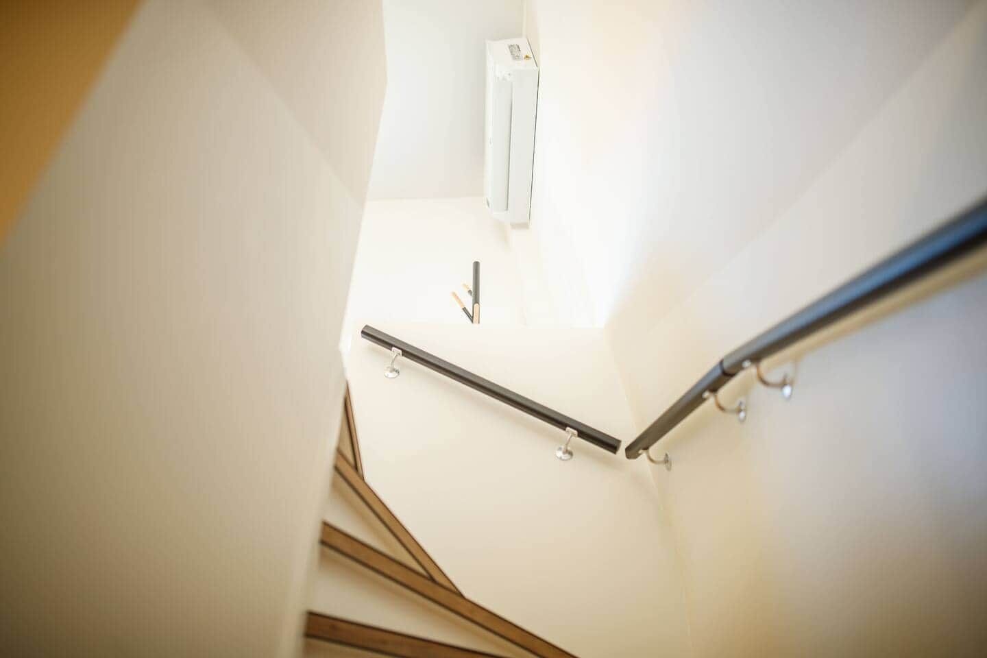 A staircase with a handrail and a light fixture on the wall.