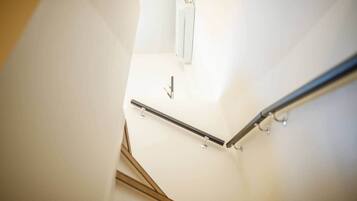A staircase with a handrail and a light fixture on the wall.